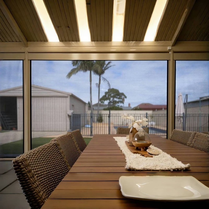 A screened outdoor dining room looking out to the yard.