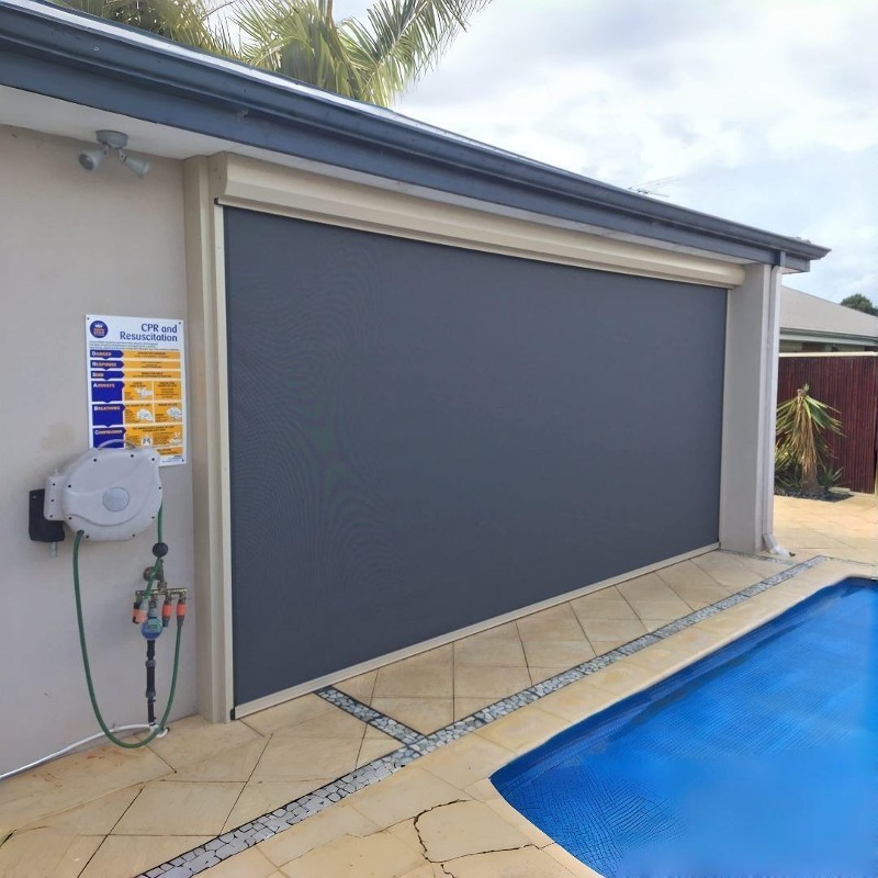 Outside surface-mount screen with housing and side tracks on a wall.
